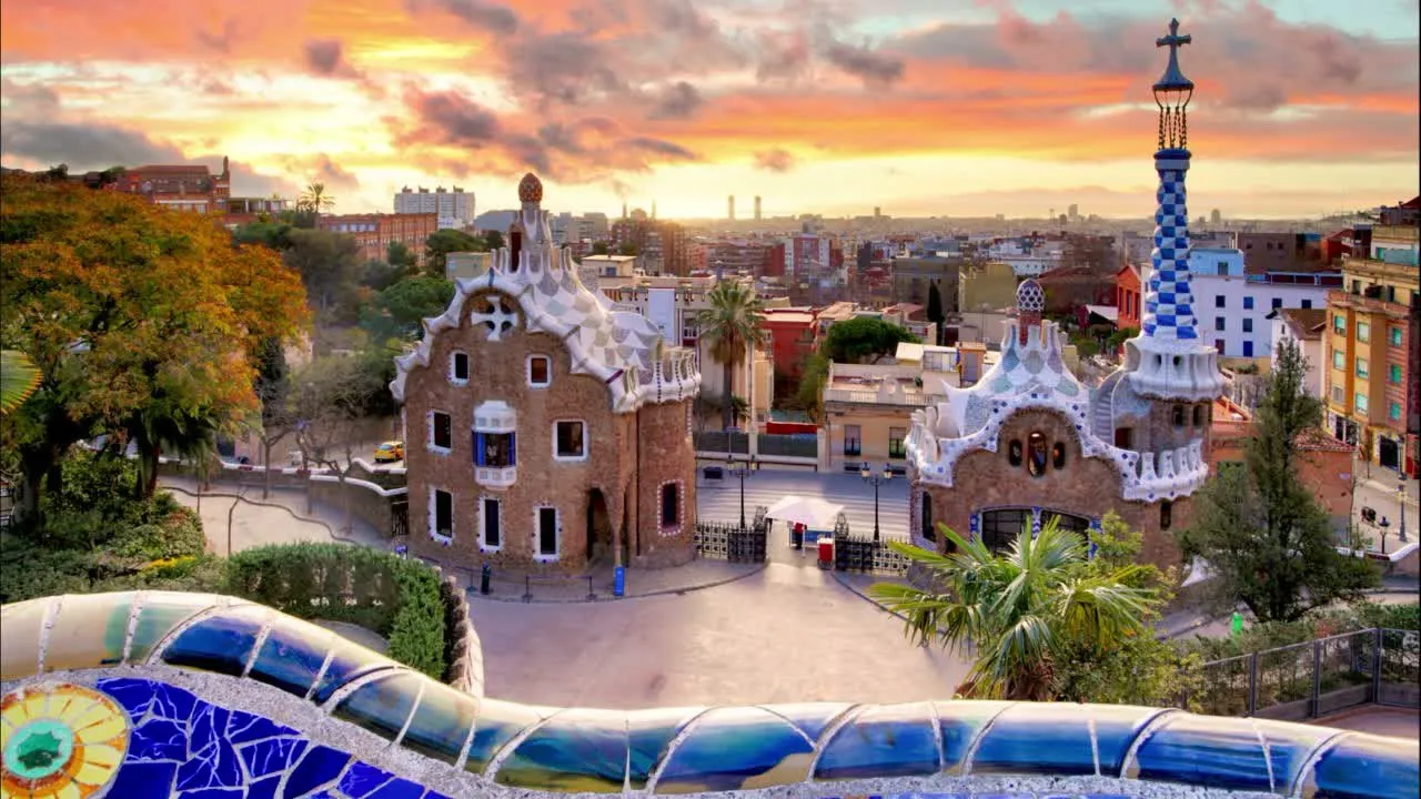 Park Güell’s mosaic terrace and gatehouses overlooking Barcelona at sunset