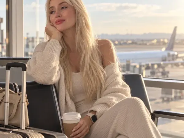 A woman resting her chin on her hand by a window with a city and sea view