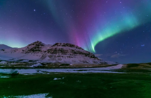 The Northern Lights over a snow-dusted mountain in Iceland