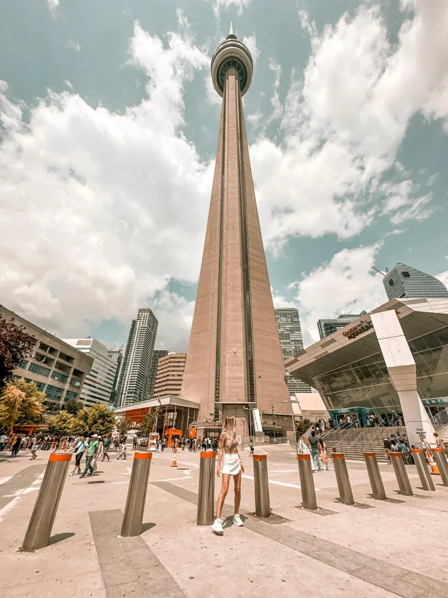 Val standing in a busy plaza beneath the CN Tower in Toronto